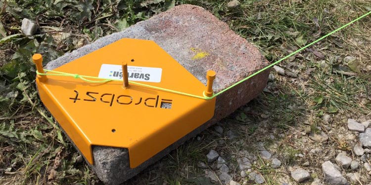 Orange Trådhållare SB med snörlinje, placerad på en sten