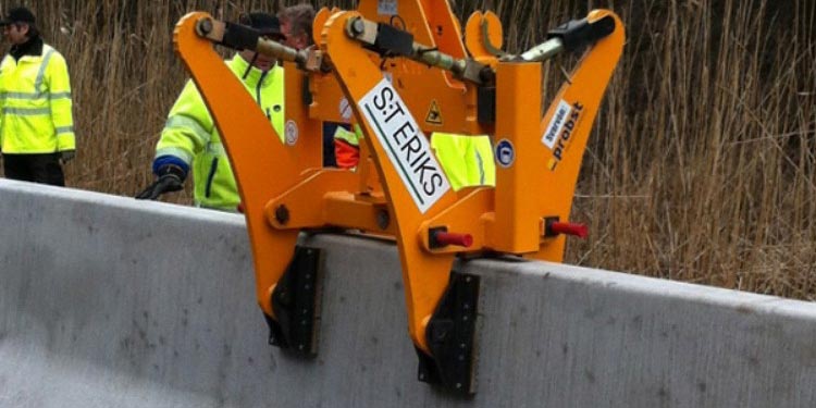 Två orange Barriärlyft BSZ som greppar en betongbarriär