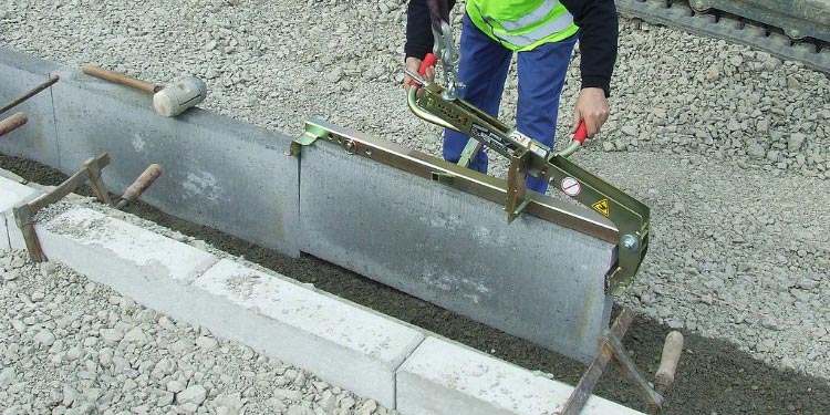 Arbetare sätter en kantsten på plats med Kantstenstång