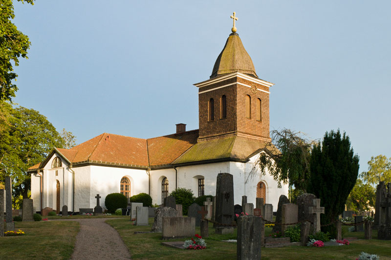 En fin kyrka i solskenet på en kyrkogård.